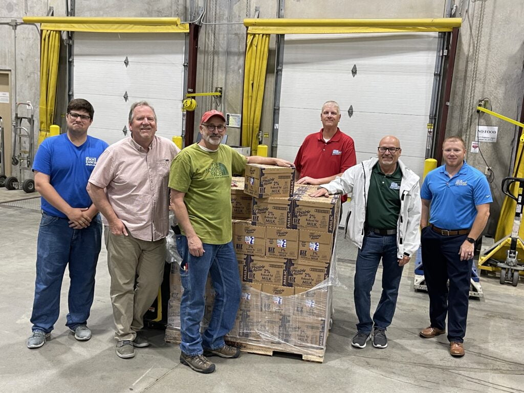 Kansas Food Bank team members accept donation of shelf-stable milk from representatives from Hiland Dairy. 