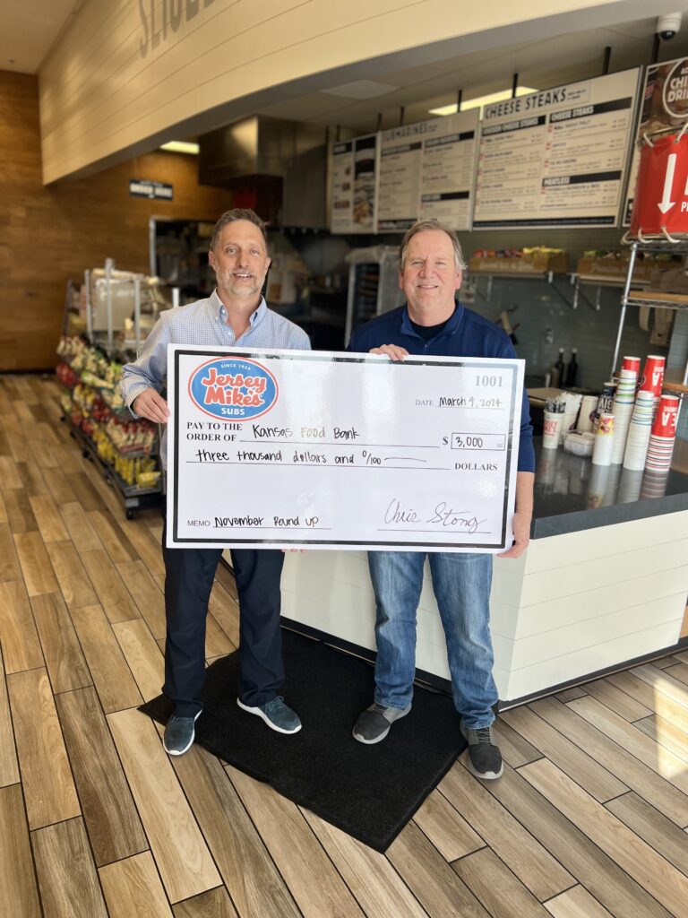 Brian Walker, President & CEO of Kansas Food Bank (right) accepts November 2023 Round Up campaign gift from Chris Stong, Jersey Mike's Franchisee.  